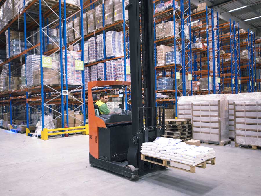 A man is transporting goods in his forklift in warehouse