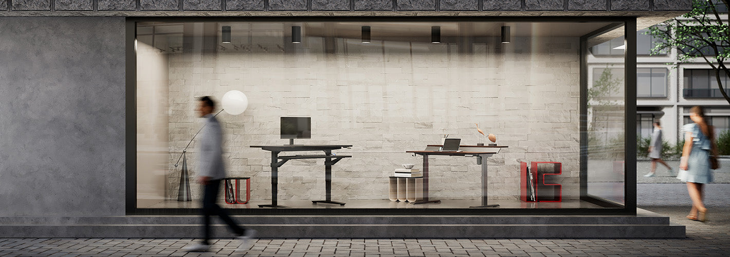 Two of fenge standing desks are displayed in a floor-to-ceiling display window along the road